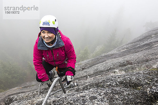 Eine Frau greift beim Klettern des Klettersteigs in Squamish  British Columbia  nach der Metallsprosse.