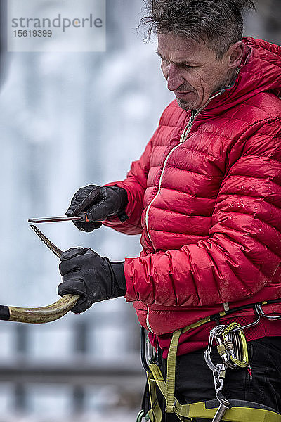 Ein Mann schärft seine Äxte für das Eisklettern vor Ort.