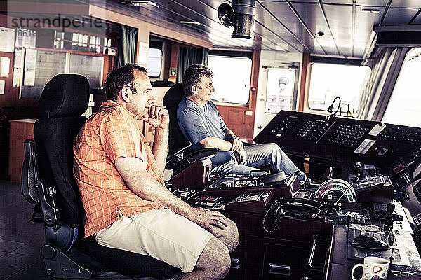 Der Kapitän und der Erste Offizier sitzen auf dem Navigationsdeck eines Containerschiffs.
