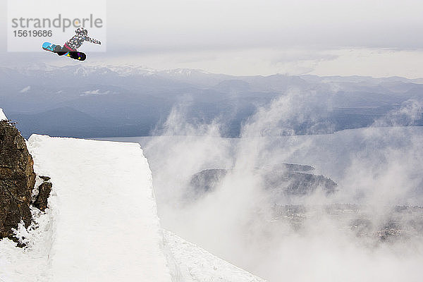 Ein weiblicher Snowboarder trifft einen Sprung am Cerro Catedral in Argentinien