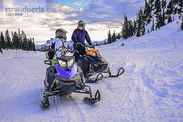Zwei abenteuerlustige Menschen unterhalten sich beim Schneemobilfahren  Callaghan Valley  Whistler  British Columbia  Kanada