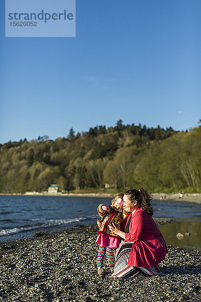 Mutter und kleine Tochter entspannen sich am felsigen Küstenstrand  Seattle  Washington  USA