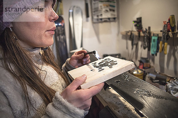 Seitenansicht einer Frau mit Strickmütze beim Wachsen von Skiern in einer Garage  Missoula  Montana  USA