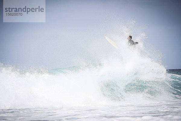 Männlicher Surfer  der einen Trick vor einer Welle an der Nordküste von Oahu bei Tageslicht macht  Hawaii  USA