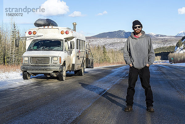 Mann in der Mitte des Alaska Highway stehend  während er nach Norden nach Alaska fährt