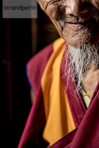 Mittelschnittaufnahme eines lächelnden älteren buddhistischen Mönchs mit weißem Bart  Boudhanath-Tempel  Kathmandu  Nepal