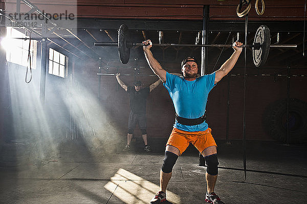 Eine Person  die Crossfit in einem alten Lagerhaus-Fitnessstudio macht  in dem Lichtstrahlen durch die Fenster eindringen.