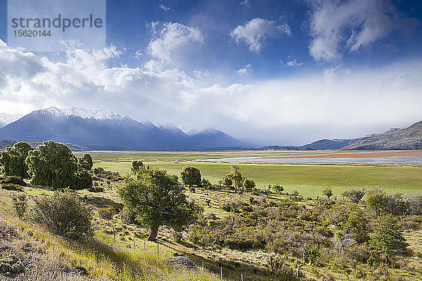 Weite  grasbewachsene Ebenen mit einem See in der Mitte bilden einen starken Kontrast zu den steilen Bergen von Chubut in Patagonien.