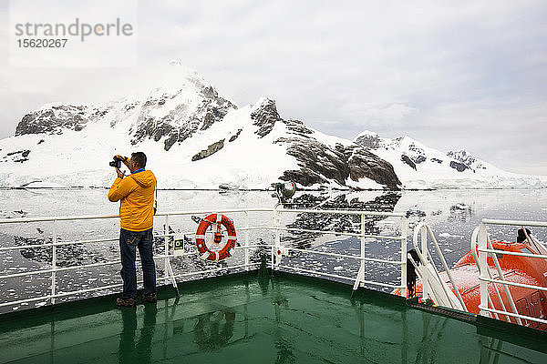 Ein Passagier auf dem Deck der Akademik Sergey Vavilov  einem eisverstärkten Schiff auf einer Expeditionskreuzfahrt in die Antarktis  vor der antarktischen Halbinsel.
