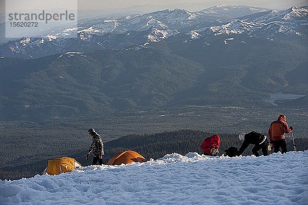 Jungen im Alter von 13 bis 17 Jahren von der Venturing Crew 191 aus Glendora  Kalifornien  setzen ein Jahr Training in die Praxis um  als sie versuchen  den Gipfel des Mount Shasta über die Avalanche Gulch-Route im Shasta Trinity National Forest in Nordkalifornien zu erreichen. Der Mount Shasta ist ein massiver  vergletscherter Vulkan und mit 14.179 Fuß der zweithöchste Gipfel in der Cascade Range und der fünfthöchste in Kalifornien; er ist mit keinem anderen Gipfel verbunden und erhebt sich abrupt 10.000 Fuß über das umliegende Gelände. Die Pfadfinder der Venturing Crew 191 (Venturing Crews sind ein Zweig der Pfadfinder  der sich auf abenteuerliche Aktivitäten konzentriert) hatten sich ein Jahr lang auf ihre Besteigung des Mount Shasta vorbereitet. Dies war ihre erste Erfahrung mit dem Klettern in steilem Schnee  und sie wurden bei ihrem Aufstieg von Führern der SWS Mountain Guides unterstützt. Josh Kolbach (links) von Venturing Crew 191 trägt im letzten Abendlicht eine Wasserflasche zurück zu seinem Zelt  während die Bergführer JB und Casey Hurden im Hochlager auf 10.000 Fuß am Mount Shasta die letzten Vorbereitungen treffen. Die Crew wird vor der Morgendämmerung aufbrechen  um den Gipfel des Mount Shasta über die Avalanche Gulch Route im Shasta Trinity National Forest  Kalifornien  zu erreichen.