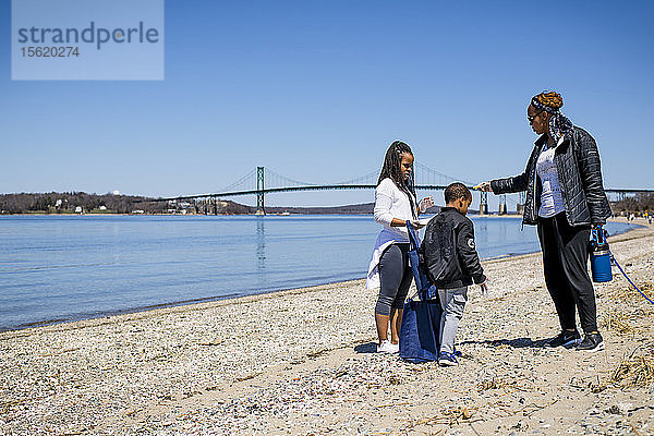 Eine Frau  ein Junge und ein Mädchen sammeln während der Strandsäuberung am Earth Day Müll auf  Portsmouth  Rhode Island  USA