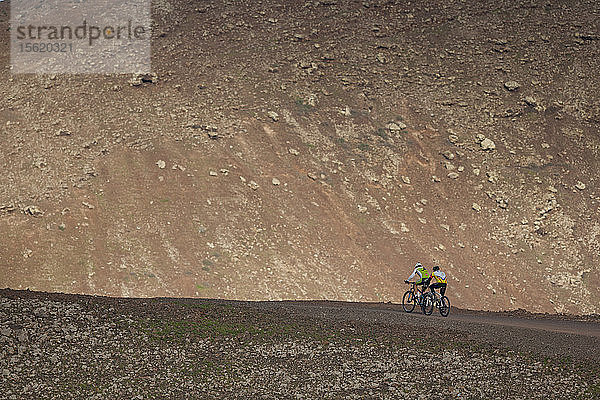 Zwei Personen mit Mountainbike beim Aufstieg auf eine Vulkan-Caldera in Fuerteventura (Kanarische Inseln)