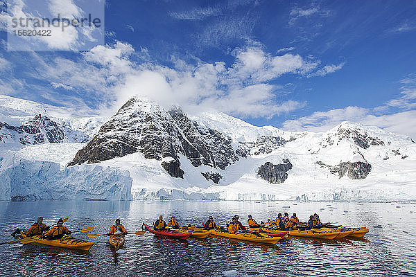 Mitglieder einer Expeditionskreuzfahrt in die Antarktis beim Seekajakfahren in der Paradise Bay unterhalb des Mount Walker auf der antarktischen Halbinsel. Die antarktische Halbinsel ist eines der sich am schnellsten erwärmenden Gebiete der Erde.