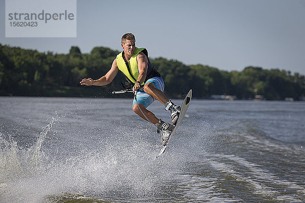 Foto eines Mannes in der Luft beim Wakeboarding auf einem Fluss