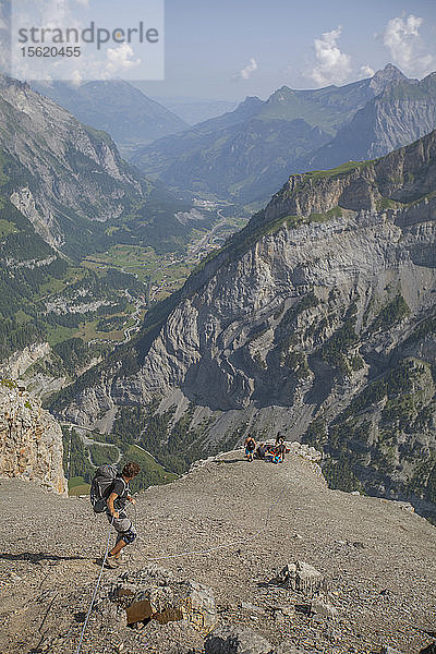Ein Pilot im Wingsuit klettert an einem Fixseil zu einem Ausstiegspunkt in den Schweizer Alpen hinunter.