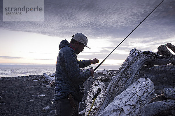 Ein Mann bereitet seine Angelrute vor Sonnenaufgang an der Lost Coast vor