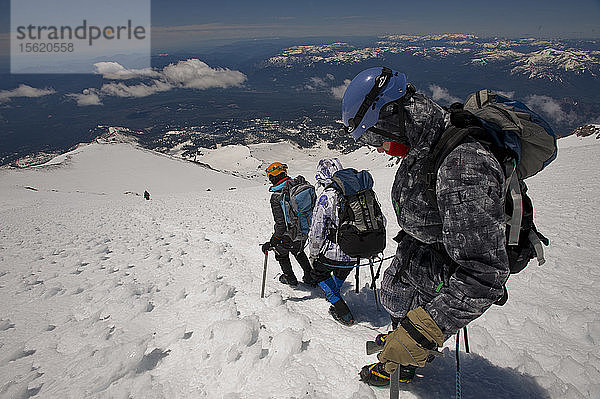 Jungen im Alter von 13 bis 17 Jahren von der Venturing Crew 191 aus Glendora  Kalifornien  setzen ein Jahr Training in die Praxis um  als sie versuchen  den Gipfel des Mount Shasta über die Avalanche Gulch-Route im Shasta Trinity National Forest in Nordkalifornien zu erreichen. Der Mount Shasta ist ein massiver  vergletscherter Vulkan und mit 14.179 Fuß der zweithöchste Gipfel in der Cascade Range und der fünfthöchste in Kalifornien; er ist mit keinem anderen Gipfel verbunden und erhebt sich abrupt 10.000 Fuß über das umliegende Gelände. Die Pfadfinder der Venturing Crew 191 (Venturing Crews sind ein Zweig der Pfadfinder  der sich auf abenteuerliche Aktivitäten konzentriert) hatten sich ein Jahr lang auf ihre Besteigung des Mount Shasta vorbereitet. Dies war ihre erste Erfahrung mit dem Klettern in steilem Schnee  und sie wurden bei ihrem Aufstieg von Führern der SWS Mountain Guides unterstützt. Josh Kolbach (rechts)  Jeremy Kolbach und Sandy Howlett von Venturing Crew 191 seilen sich ab  um die steilen  vereisten Hänge oberhalb von Avalanche Gulch abzusteigen  auf ihrem Abstieg vom Gipfel des Mount Shasta  14.179 Fuß - der gesamte Aufstieg vom Hochlager aus dauerte fast 14 Stunden und umfasste 4200 Fuß Aufstieg  Shasta Trinity National Forest  Kalifornien.
