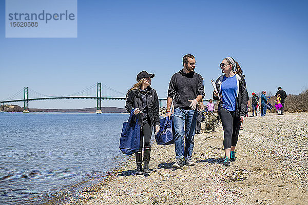 Zwei Frauen und ein Mann gehen mit Müllsäcken bei der Strandsäuberung am Earth Day  Portsmouth  Rhode Island  USA
