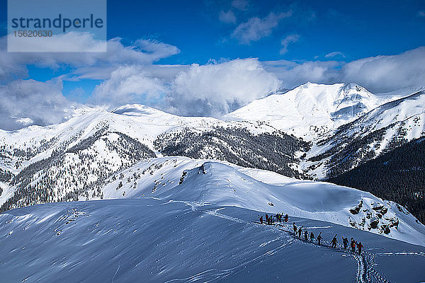 Eine Gruppe von Skifahrern und Snowboardern wandert auf den Gipfel des Silverton Mountain in Colorado.