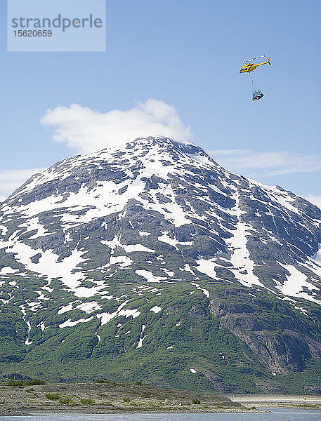 Hubschrauber fliegt eine Ladung Rafting-Ausrüstung über den Tweedsmuir-Gletscher und am Turnback Canyon vorbei  Alsek River