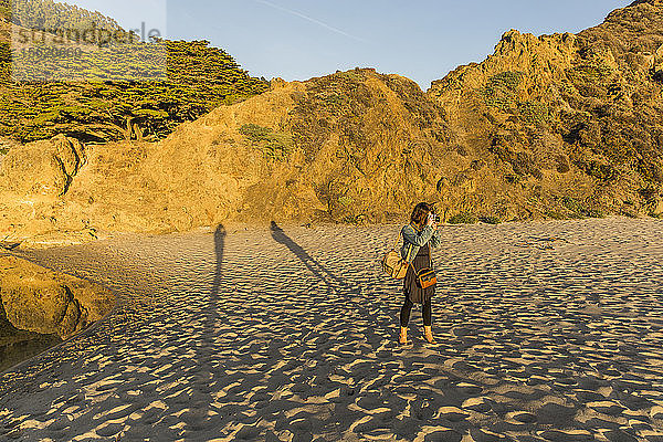Eine junge Frau macht ein Foto am Strand von Big Sur  Kalifornien