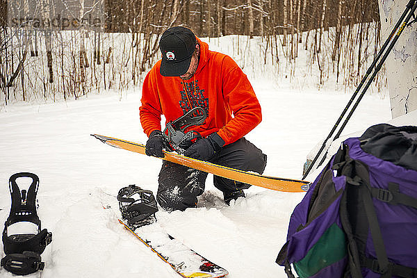 Ein Mann nimmt die Felle von seinem Splitboard im Hinterland von Vermont ab.