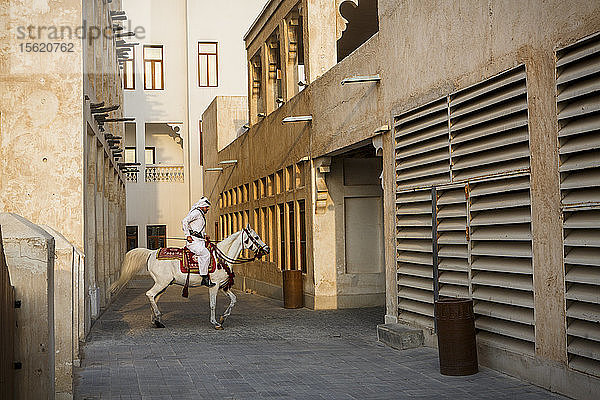 Mann in traditioneller arabischer Kleidung reitet auf einem Pferd im Souq Waqif  Doha  Katar