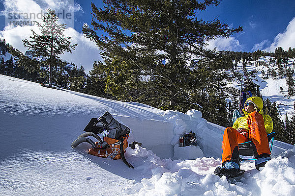 Eine junge Frau entspannt sich nach einer Skitour und gräbt Lawinengruben