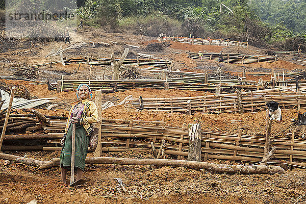 Eine ältere Frau steht am Fuße einer Reihe von Bauplattformen  die von einem Bambusgerüst gehalten werden  an der provisorischen Umsiedlungsstelle oberhalb von Muang Va  Laos. Das Dorf wird durch den Staudamm Nr. 6 des Nam Ou-Flusses vollständig überflutet werden  und die von der Regierung bereitgestellte Umsiedlungsstelle in der Nähe von Hat Sa wird nicht rechtzeitig fertiggestellt werden.