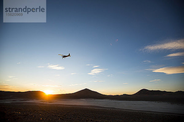 Flugzeug fliegt gegen den Himmel bei Sonnenuntergang über der Wüste von Nevada
