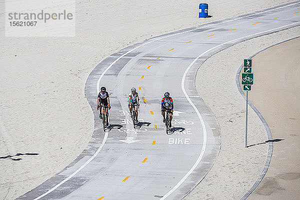 Vorderansicht von drei Radfahrern  die nebeneinander auf dem Radweg fahren