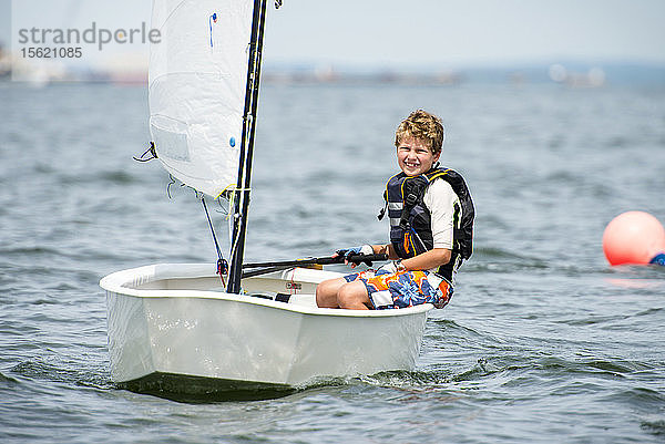 Lächelnder Teenager  der sich in der Narragansett Bay im Sommer-Junior-Segelprogramm vergnügt