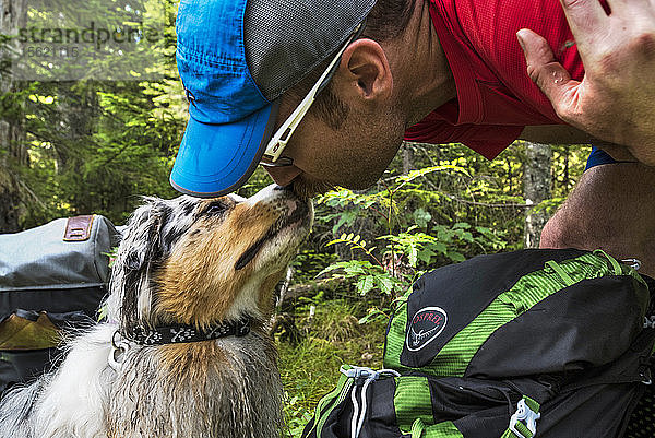 Nahaufnahme des Mannes küssen auf seinen Hund Nase im Wald beim Wandern