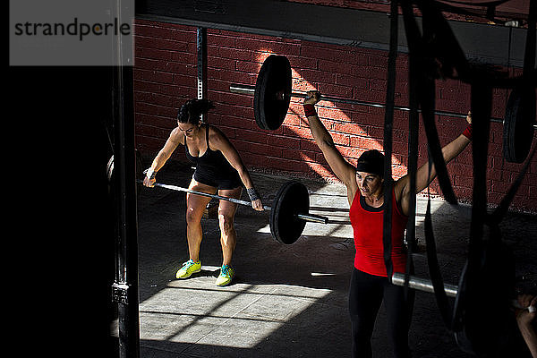 Zwei Frauen trainieren in einem Crossfit-Fitnessstudio.