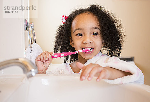 Ein junges  multikulturelles Mädchen putzt sich die Zähne.