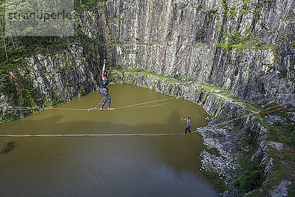 Abenteuerlustiger Mann und abenteuerlustige Frau überqueren den Steinbruch in entgegengesetzter Richtung auf getrennten Slacklines  Steinbruch Dibs  Maripora  Bundesstaat Sao Paulo  Brasilien
