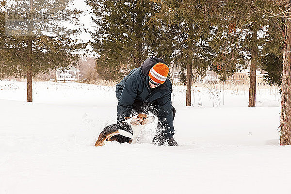 Mann beim Schneeschuhwandern im Wald mit seinem Beagle