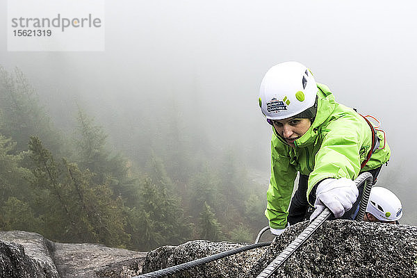 Eine Frau greift beim Klettern des Klettersteigs in Squamish  British Columbia  nach der Metallsprosse.