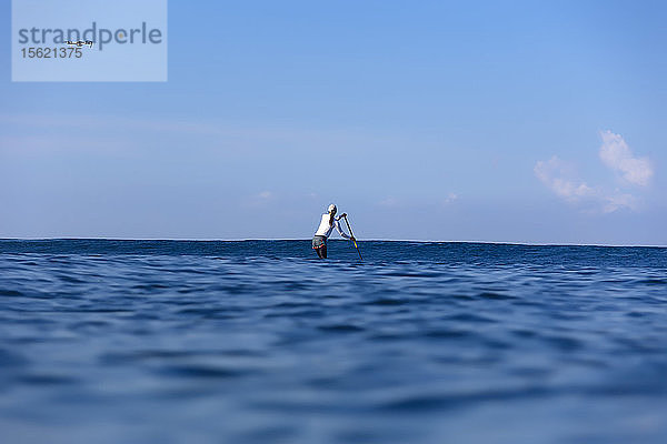 Entfernte Ansicht Schuss von Frau Paddel Surfen im Meer