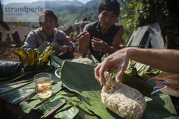 Robert Hahn bedient sich beim Mittagessen auf einer Baustelle für ein neues Haus in Ban Phak Kung  Laos  an Klebreis. Viele Mitglieder der Gemeinde helfen mit und werden mit einer Mahlzeit bedankt.