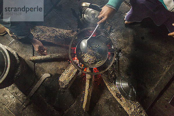 Direkt über der Ansicht von Menschen  die in einem Haus über einem kleinen Lagerfeuer kochen  Myanmar  Shan  Myanmar