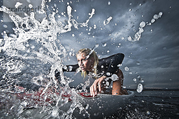 Eine Paddelboarderin paddelt durch die Wellen in San Diego  CA.