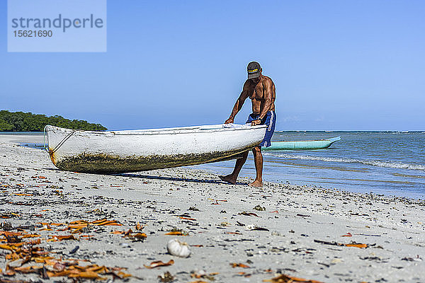 Foto eines Mannes ohne Hemd  der ein Boot ins Meer zieht  Morro de Sao Paulo  Bahia  Brasilien