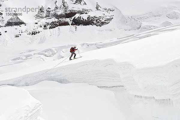 Das Team trägt einen Cache am Eisfall vorbei auf 11.000 Fuß Höhe bei einer Skibesteigung des Mount Sanford Sheep Glacier Route im Wrangell-St. Elias National Park außerhalb von Glennallen  Alaska Juni 2011. Der Mount Sanford ist mit 16.237 Fuß der sechsthöchste Berg in den Vereinigten Staaten. (Modellfreigabe: Patrick Gilroy und Adam Howard)