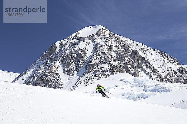 Ein Bergsteiger lächelt beim Abfahren eines Gletscherhangs in 12.000 Fuß Höhe am Denali in Alaska.