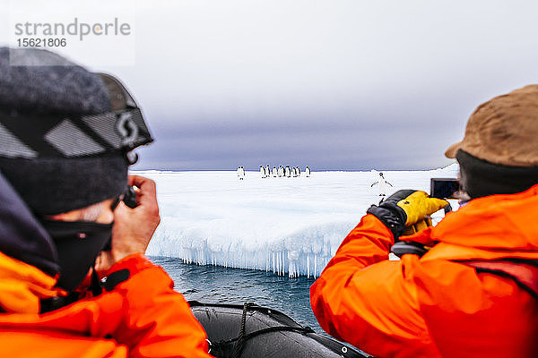 Zwei Männer fotografieren Pinguine auf einem Eisberg  Bay of Whales  Ross Sea  Antarktis