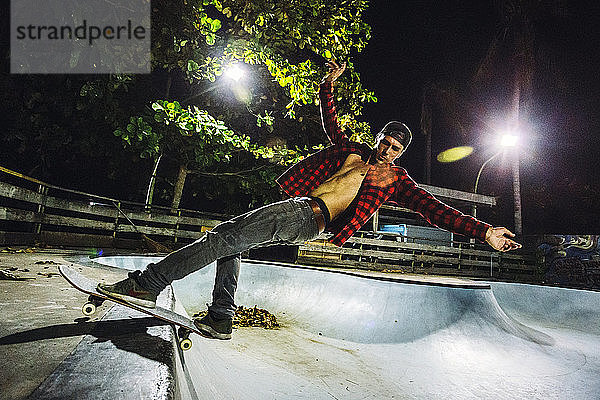 Seitenansicht eines Mannes beim Skateboardfahren in einem beleuchteten Skatepark bei Nacht  Jimbaran  Bali  Indonesien