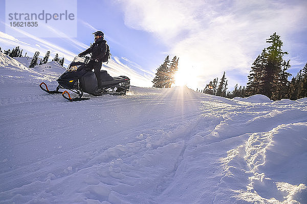Seitenansicht eines abenteuerlustigen Mannes beim Schneemobilfahren im Callaghan Valley  Whistler  British Columbia  Kanada