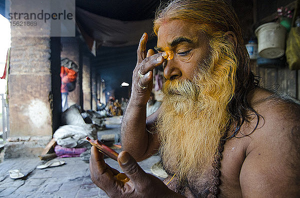 Ein schiwitischer Hindu-Heiliger trägt im Pashupatinath-Tempel in Nepal symbolische Farbe auf sein Gesicht auf