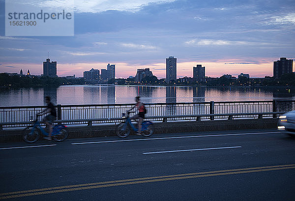 Seitenansicht von zwei Radfahrern auf einer Brücke über den Charles River bei Sonnenuntergang  Boston  Massachusetts  USA